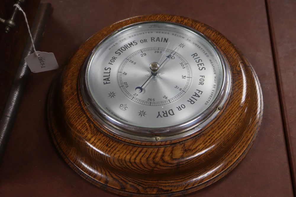 An oak stationery cabinet with brass monograms, 39 x 36cm, together with an oak aneroid barometer